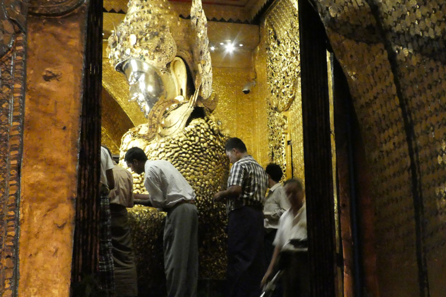 Les fidèles posent des feuilles d'or sur le Bouddha